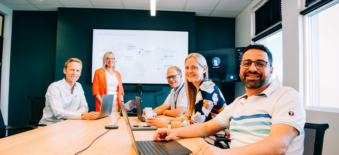 A group of Jotron employees sitting in a meeting room.
