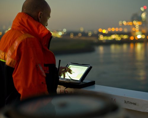 Maritime pilot navigating on deck using a screen.