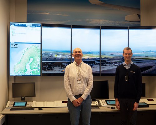 Jotron employees in front of large ATC screens in the company's demoroom.