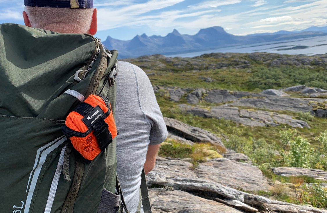 Man on mountain with PLB on his backpack