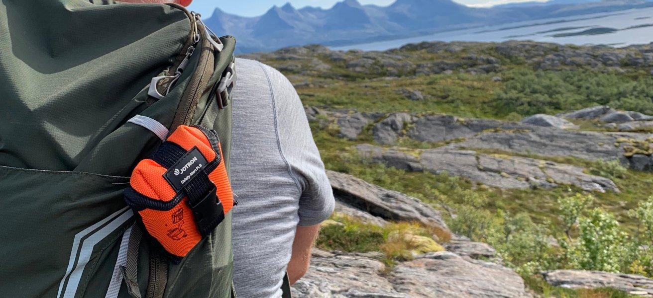 Man on mountain with PLB on his backpack
