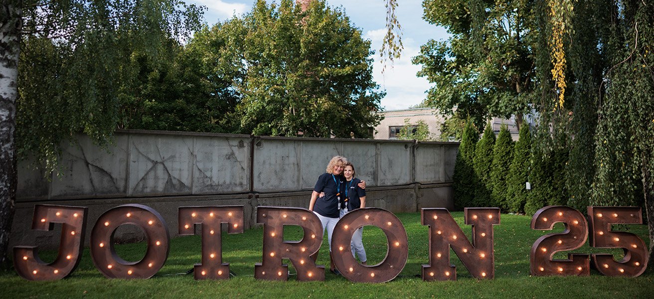 Alma and Aurelija, UAB Jotron in front of illuminated sign "Jotron 25".