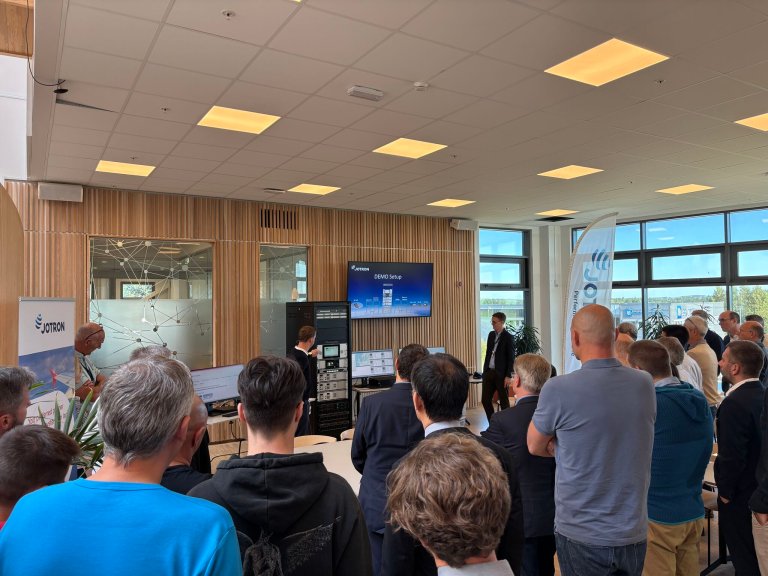 People standing and listening to a ATC radio presentation by Jotron at the VOTE meeting in Larvik.