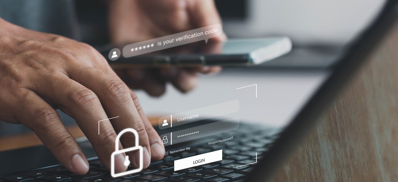 A photo illustrating cybersecurity, showing hands on a PC keyboard with login and security symbols displayed on the screen.
