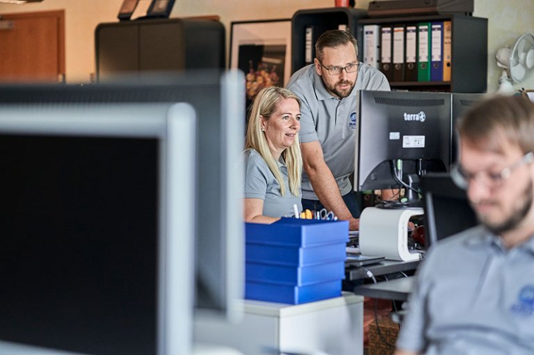 Three employees in the office, working in front of the PC's 
